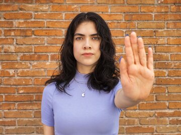 Frau hält ihre Hand vor die Kamera und signalisiert damit "Stopp" | © Getty Images/Sergio Mendoza Hochmann 