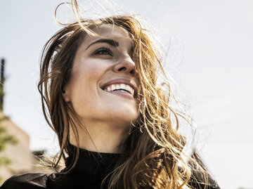 Aufnahme einer lächelnden jungen Frau, deren Haare vom Wind zerzaust sind | © Getty Images/Westend61