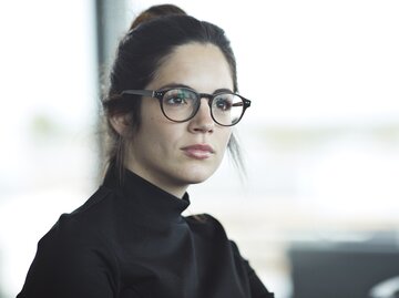 Frau trägt schwarzen Rollkragenpullover, Zopf und Brille. Sie schaut fokussiert. | © Getty Images/Klaus Vedfelt