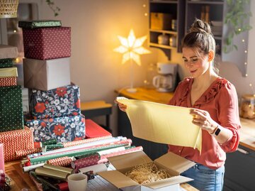 Frau verpackt Weihnachtsgeschenke | © Getty Images/svetikd