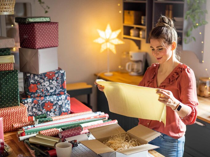 Frau verpackt Weihnachtsgeschenke | © Getty Images/svetikd