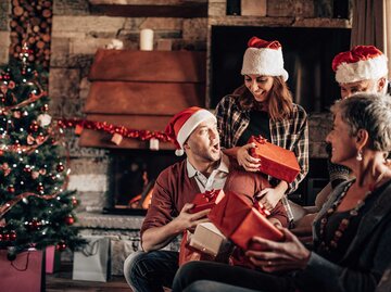 Familie sind an Weihnachten zusammen und trägt rote Weihnachtsmann-Mützen. | © Getty Images / franckreporter