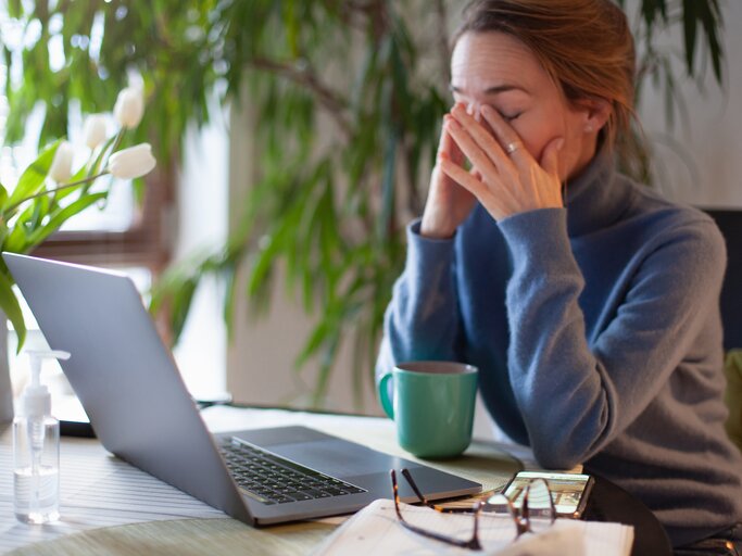 Frau sitzt am Schreibtisch und ist erschöpft von der Arbeit | © Getty Images/Kathrin Ziegler