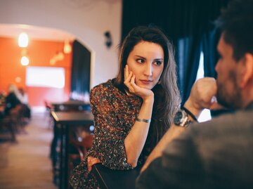 Frau sitzt bei einem Date und schaut ihren Gegenüber skeptisch an | © Getty Images/lechatnoir