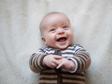 Kleines, süßes, lachendes Baby liegt auf dem Rücken | © Getty Images/Westend61