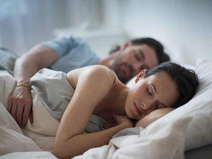 Frau und Mann liegen gemeinsam schlafend im Bett. | © Getty Images / Tetra Images