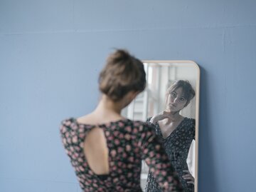 Frau steht nachdenklich vor dem Spiegel  | © Getty Images/Westend61