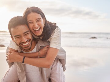 Junger Mann trägt Frau Huckepack. Beide lachen | © Getty Images/PeopleImages
