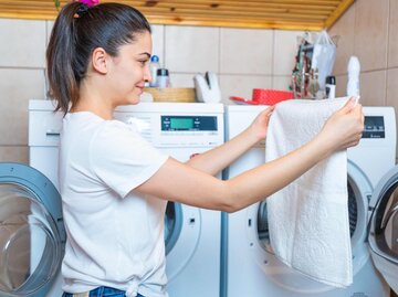 Frau betrachtet Wäsche aus der Waschmaschine | © Getty Images/aquaArts studio