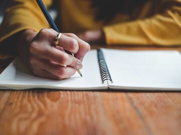 Person schreibt mit Bleistift auf Linienpapier | © Nattakorn Maneerat