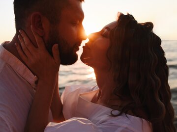 Mann und Frau küssen sich bei Sonnenuntergang | © Getty Images/MarynaTerletska