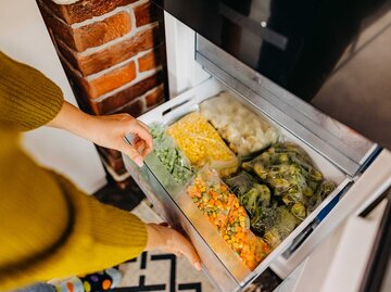 Frau öffnet eine Schublade im Eisfach mit Gemüse. | © Getty Images / StefaNikolic