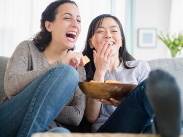 Zwei Frauen lachen gemeinsam, während sie einen Film schauen | © Getty Images/JGI/Jamie Grill
