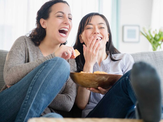 Zwei Frauen lachen gemeinsam, während sie einen Film schauen | © Getty Images/JGI/Jamie Grill