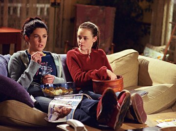 Szene aus Gilmore Girls: Rory und Lorelai sitzen auf der Couch und gucken fernsehen | © IMAGO / Cinema Publishers Collection