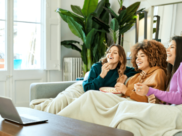 Drei Frauen schauen Film auf Laptop | © Getty Images/Morsa Images