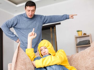 Papa beschimpft ein ungezogenes Teenager-Mädchen. Ein widerspenstiges Kind zeigt seinem Vater den Mittelfinger | © Getty Images/TatyanaGl