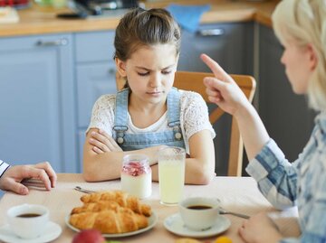 Mutter schimpft mit Tochter am Esstisch | © Getty Images/shironosov