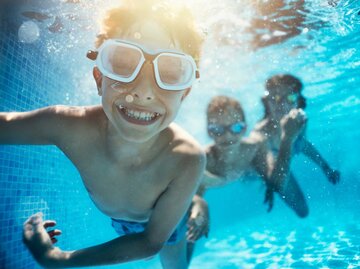 Kinder spielen unter Wasser im Pool | © Getty Images/Imgorthand