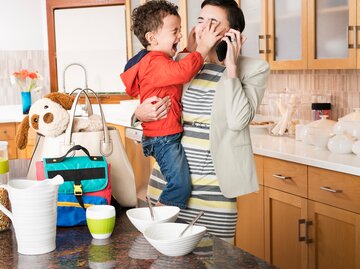 Eine Frau hat ihren weinenden Sohn auf dem Arm und telefoniert | © GettyImages/Ariel Skelley