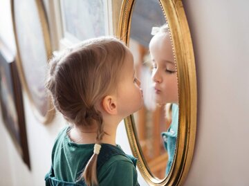 Kind küsst Spiegelbild | © Getty Images/Elva Etienne