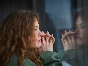 Frau mit roten Haaren schaut grübelnd aus dem Fenster | © Getty Images/Justin Case