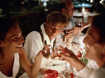 Eine Gruppe von Freunden sitzt abends gemeinsam am Tisch, ein Mann ist eifersüchtig. | © Getty Images / Bob Thomas