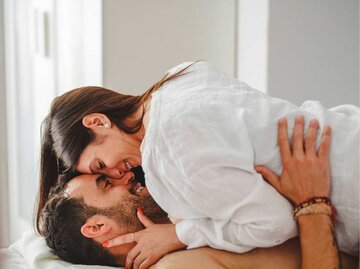Paar liegt aufeinander im Bett und küsst sich leidenschaftlich | © Imago/Addictive Stock