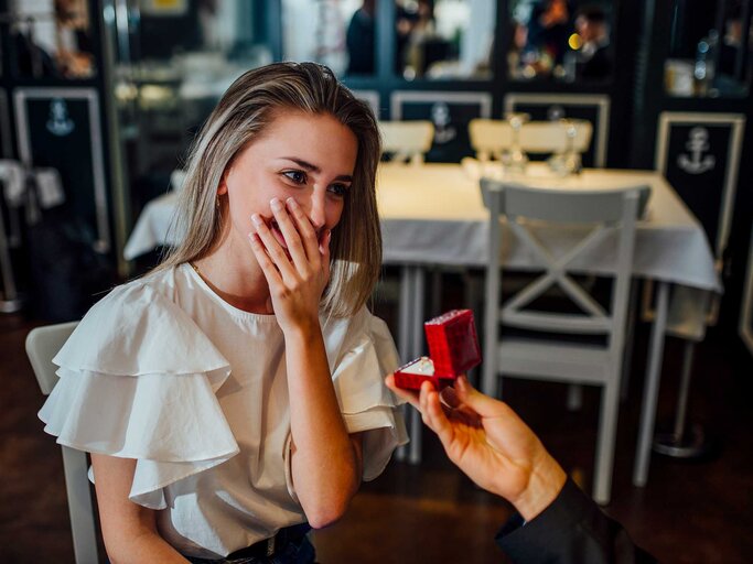 Frau mit weißer Bluse bekommt im Restaurant einen Heiratsantrag. | © Getty Images / Jose Luis Agudo Gonzalez