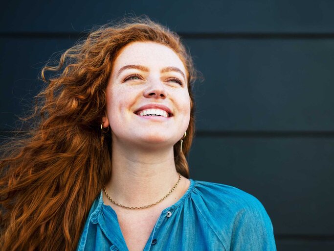 Frau mit roten Locken blickt optimistisch in die Ferne | © Getty Images/Tim Robberts