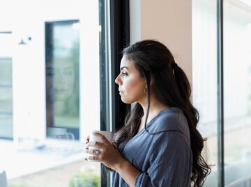 Frau steht nachdenklich vor dem Fenster | © Getty Images/SDI Productions