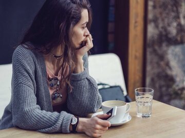 Frau sitzt nachdenklich in einem Cafe | © Getty Images/Mixmike