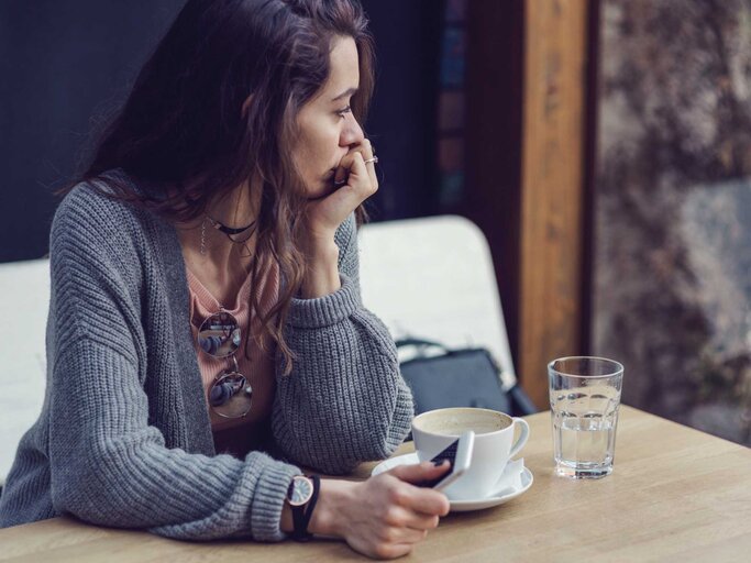 Frau sitzt nachdenklich in einem Cafe | © Getty Images/Mixmike