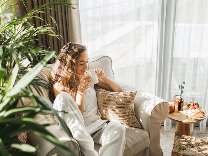 Person sitzt in Sessel mit Tasse | © Getty Images/Anastasiia Krivenok