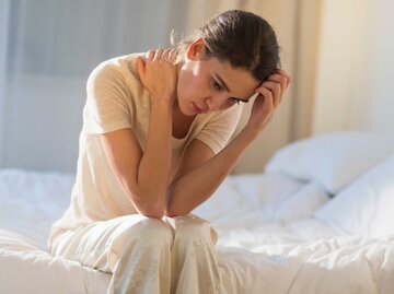 Frau sitzt nachdenklich auf ihrem Bett | © Getty Images/Tetra Images