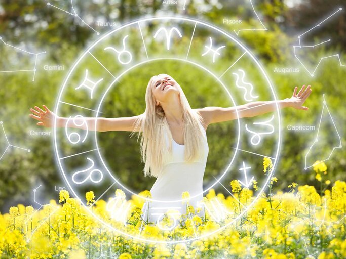 Blonde Frau steht im Rapsfeld mit offenen Armen inmitten eines Astro-Rings | © Getty Images/AndreyPopov