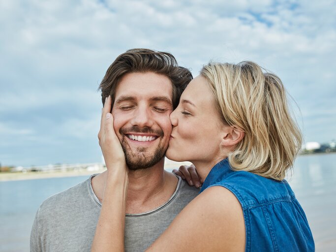 Eine Frau gibt einem Mann einen Kuss auf die Wange | © GettyImages/Westend61