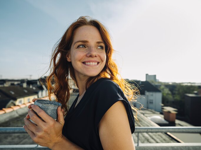 Eine junge Frau schaut strahlend und gebannt nach hinten | © GettyImages/Westend61