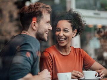 Mann und Frau sitzen zusammen im Café und lachen | © Getty Images/Westend61