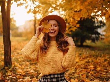 Person mit Herbstlaub | © Getty Images/Elizaveta Starkova