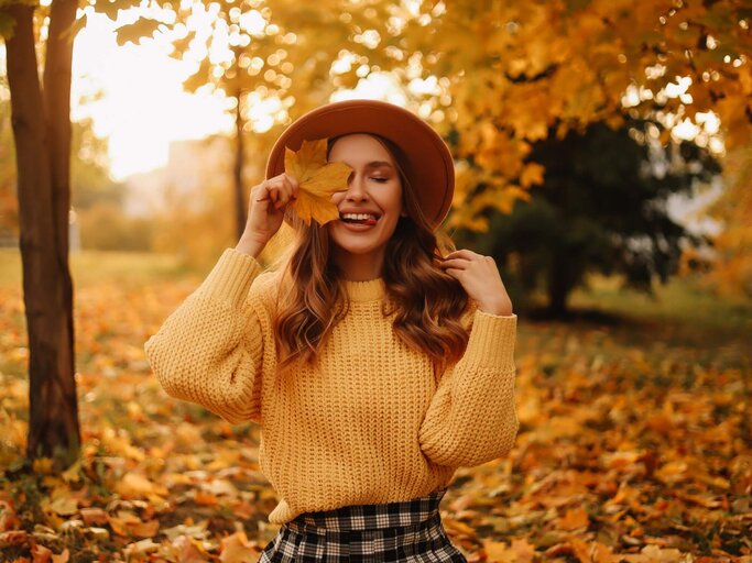 Person mit Herbstlaub | © Getty Images/Elizaveta Starkova
