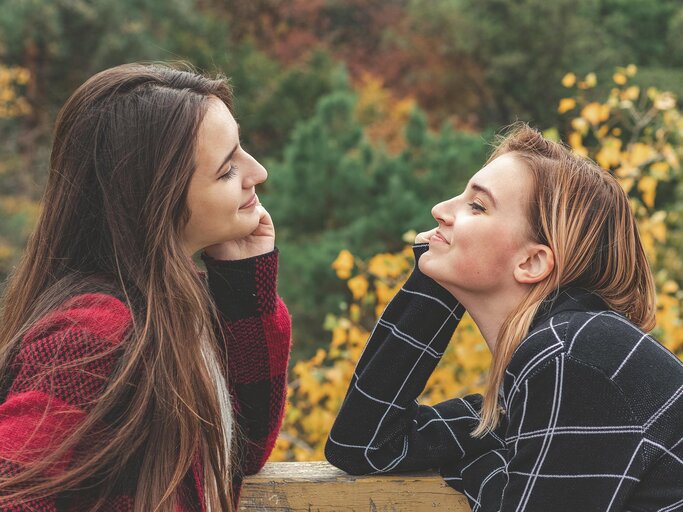 Zwei Frauen sitzen sich gegenüber und lächeln sich an | © AdobeStock/Victoria Kondysenko