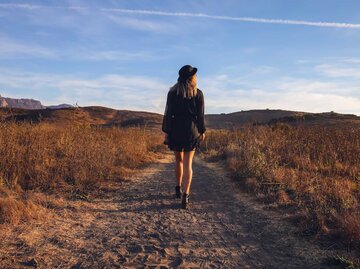 Frau in schwarzem Kleid und Hut auf dem Feld | © Getty Images/Dianne Avery Photography