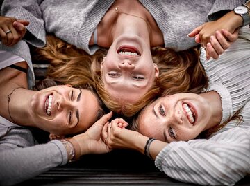 Drei Freunde liegen Kopf an Kopf | © Getty Images/Oliver Rossi