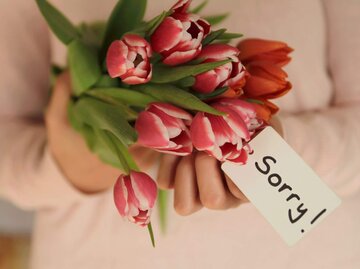 Person mit Blumen und Sorry-Schild | © Getty Images/Isabel Pavia