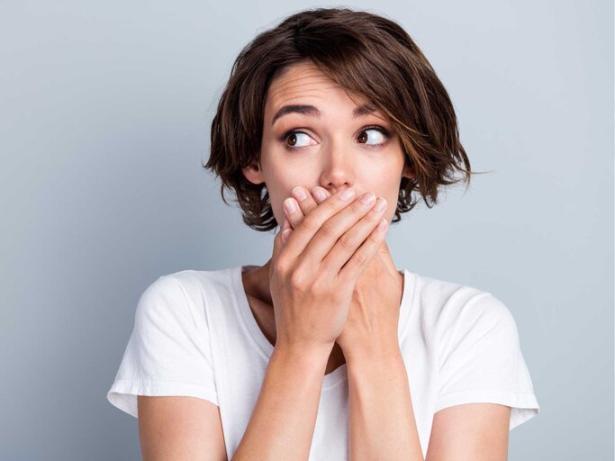 Frau hält sich erschrocken den Mund zu | © Adobe Stock/deagreez