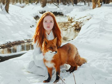 Eine junge rothaarige Frau mit einem Fuchs in der Natur | © Getty Images / Marie Dashkova 