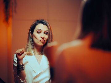 Frau steht undankbar und unzufrieden vor dem Spiegel. | © Adobe Stock/nicoletaionescu
