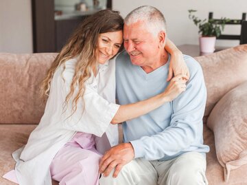 Erwachsene Tochter umarmt Vater auf der Couch. | © Adobe Stock/Tatyana Gladskih