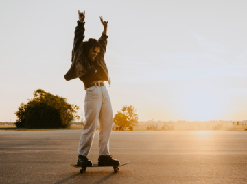 Frau bei Sonnenuntergang auf dem Skateboard | © Getty Images/Maskot